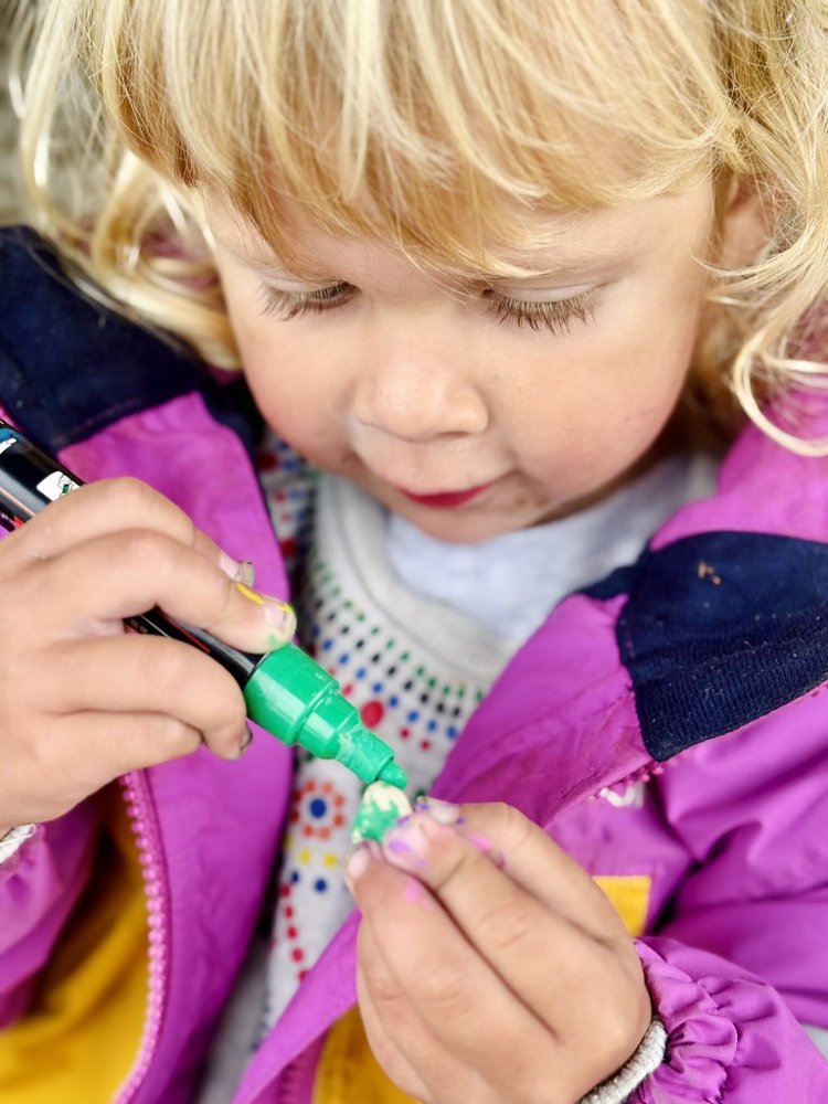 Een kleuter kleurt geconcentreerd met een groene stift
